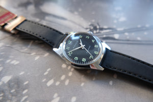Wristwatch with black strap and silver case on a textured surface